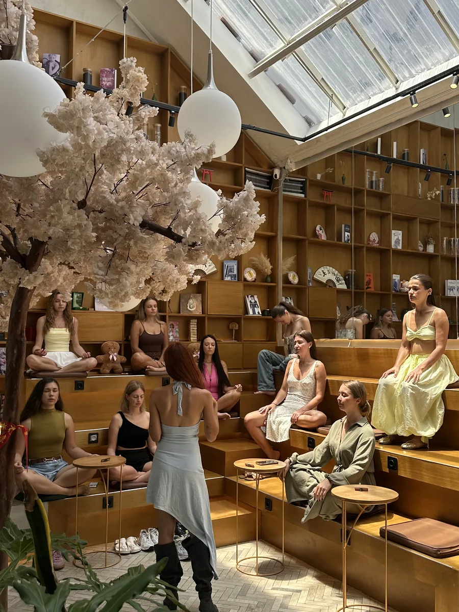 Tiered wooden seating under the cherry blossom tree, lit by the skylight